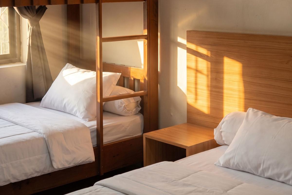 Bunk bed and double bed with white linen in warm afternoon light.